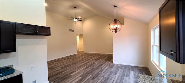 interior space featuring light stone counters, ceiling fan with notable chandelier, dark wood-type flooring, decorative light fixtures, and high vaulted ceiling