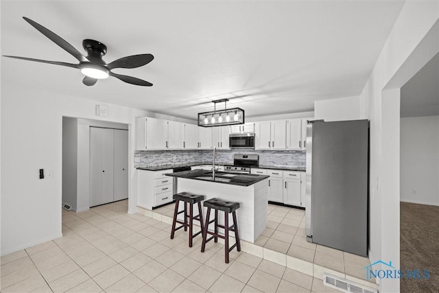 kitchen with white cabinetry, a center island, ceiling fan, stainless steel appliances, and tasteful backsplash