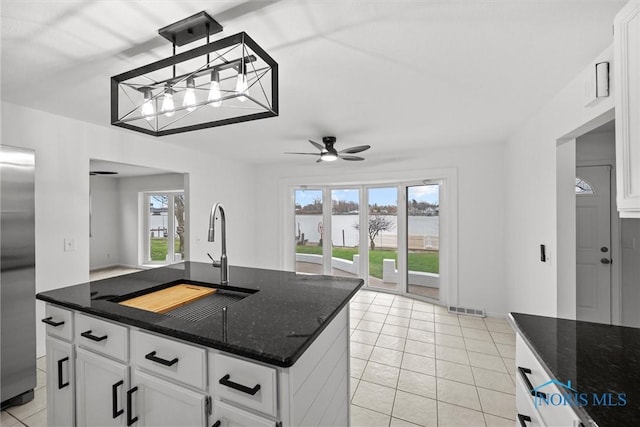 kitchen with ceiling fan, sink, pendant lighting, dark stone countertops, and white cabinets