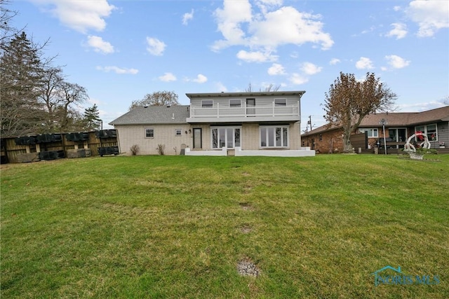 rear view of property featuring a yard and a balcony