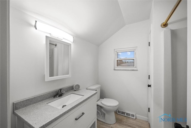 bathroom with tile patterned flooring, vanity, toilet, and lofted ceiling