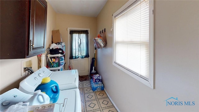 clothes washing area with washing machine and clothes dryer, light tile patterned floors, and cabinets