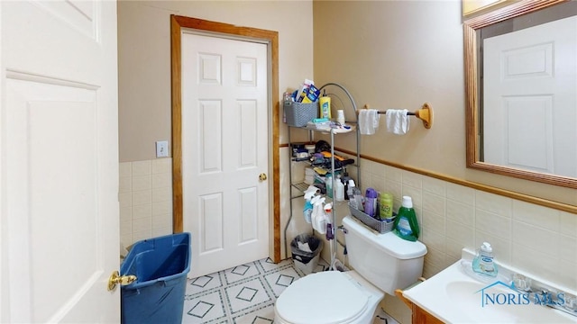 bathroom with vanity, toilet, and tile walls