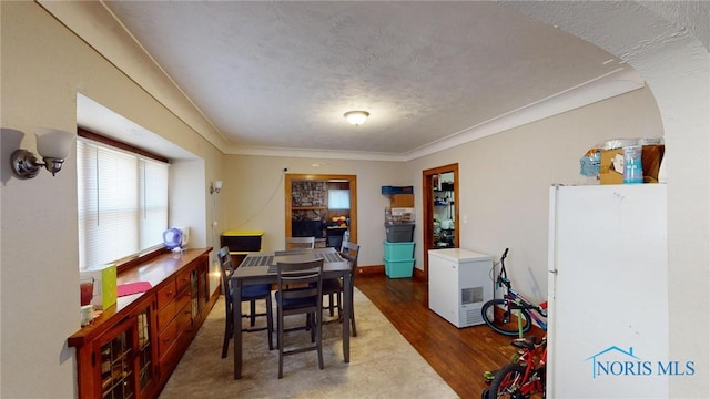 dining space featuring dark hardwood / wood-style floors, crown molding, and a textured ceiling