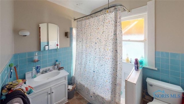 full bathroom with vanity, shower / bath combination with curtain, toilet, and tile walls