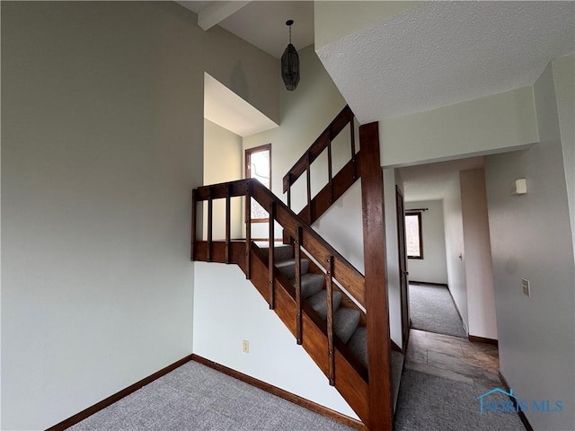 stairway featuring carpet, a textured ceiling, and a high ceiling