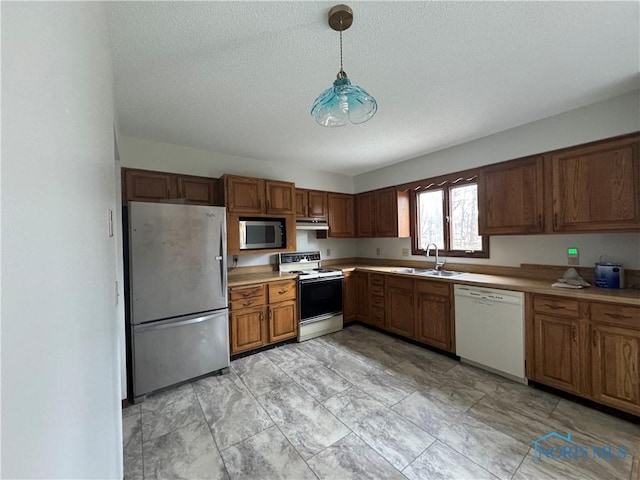 kitchen featuring hanging light fixtures, sink, stainless steel appliances, and a textured ceiling