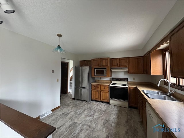 kitchen with a textured ceiling, hanging light fixtures, sink, and appliances with stainless steel finishes