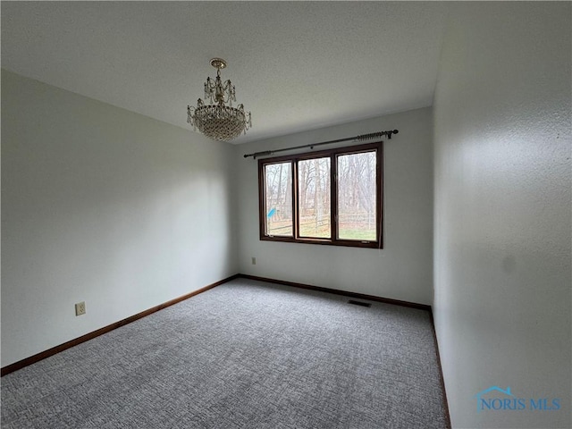 carpeted spare room with an inviting chandelier