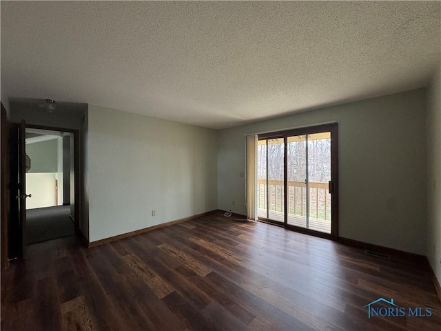 spare room featuring dark hardwood / wood-style floors and a textured ceiling