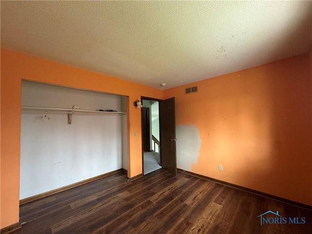 unfurnished bedroom featuring dark hardwood / wood-style flooring, a closet, and a textured ceiling