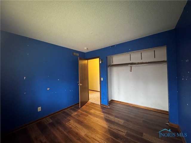 unfurnished bedroom featuring a textured ceiling, dark hardwood / wood-style floors, and a closet