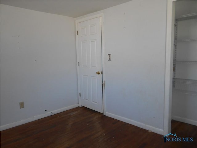 unfurnished bedroom with a closet and dark hardwood / wood-style floors