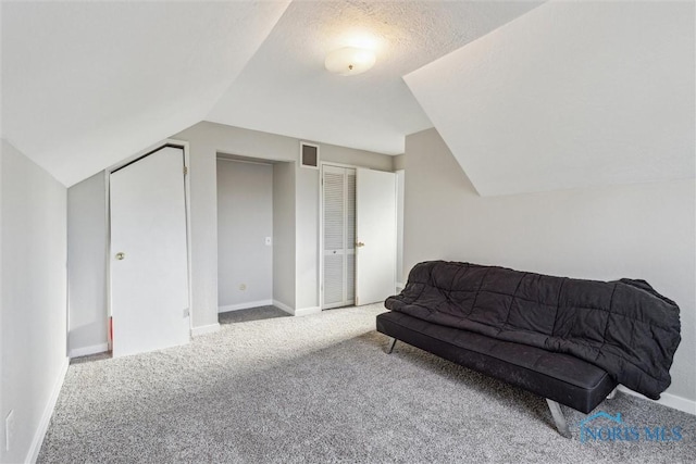 living area featuring carpet flooring, a textured ceiling, and vaulted ceiling