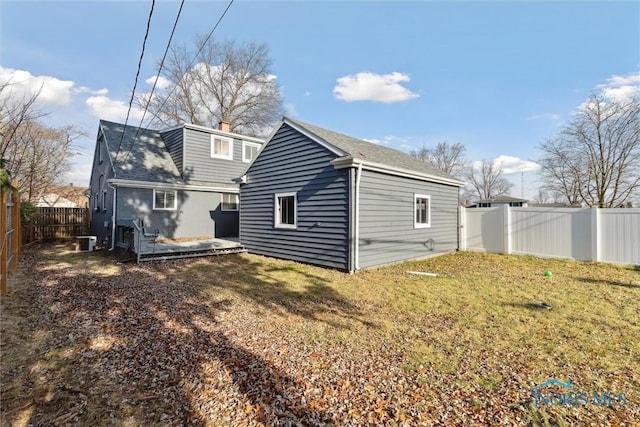 rear view of property featuring cooling unit and a yard