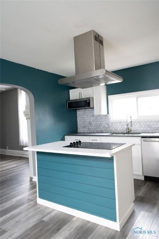 kitchen with appliances with stainless steel finishes, white cabinetry, a kitchen island, and range hood