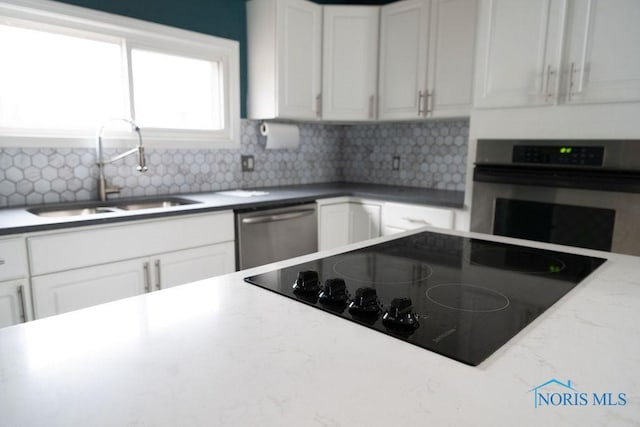 kitchen with white cabinets, stainless steel appliances, tasteful backsplash, and sink