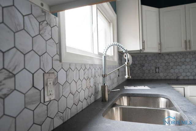 kitchen featuring decorative backsplash, white cabinetry, and sink