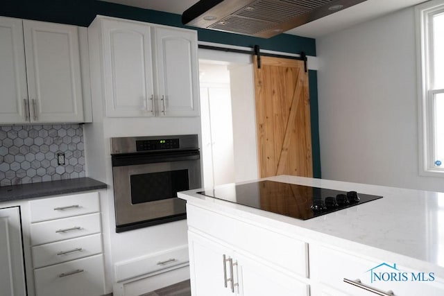 kitchen with stainless steel oven, a barn door, decorative backsplash, black electric stovetop, and white cabinets