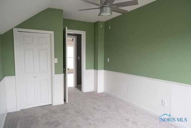 unfurnished bedroom with ceiling fan, a closet, light colored carpet, and lofted ceiling