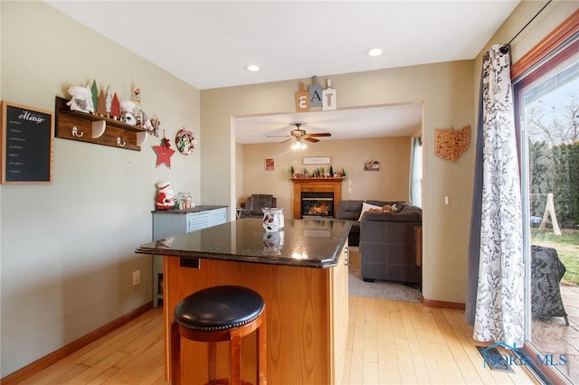 kitchen with a breakfast bar, a center island, ceiling fan, and light hardwood / wood-style flooring