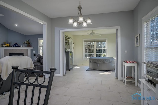 dining room with light tile patterned floors and ceiling fan with notable chandelier