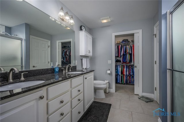 bathroom featuring toilet, tile patterned flooring, vanity, and walk in shower