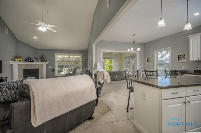 interior space with a tile fireplace, ceiling fan with notable chandelier, and lofted ceiling