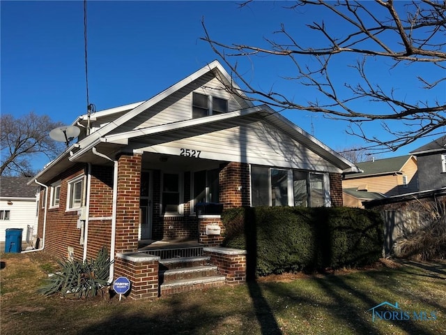 bungalow featuring covered porch and a front yard