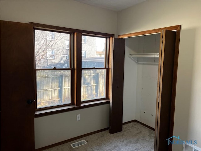 unfurnished bedroom featuring light carpet and a closet