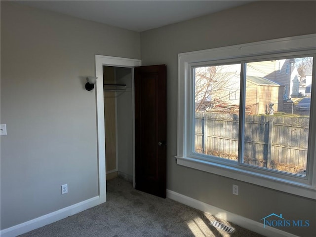 unfurnished bedroom featuring carpet flooring, multiple windows, and a closet