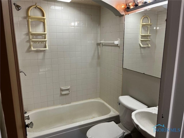 full bathroom featuring tiled shower / bath combo, toilet, and sink