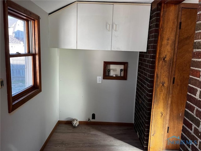 clothes washing area featuring cabinets, dark wood-type flooring, washer hookup, and brick wall