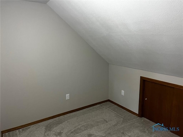 bonus room with a textured ceiling, carpet floors, and lofted ceiling