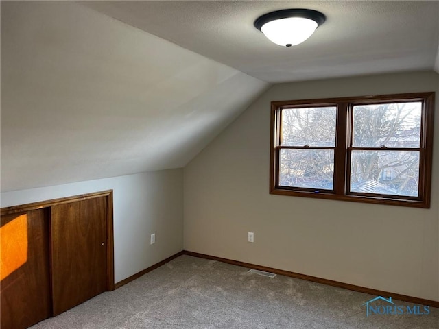 bonus room featuring light carpet and vaulted ceiling