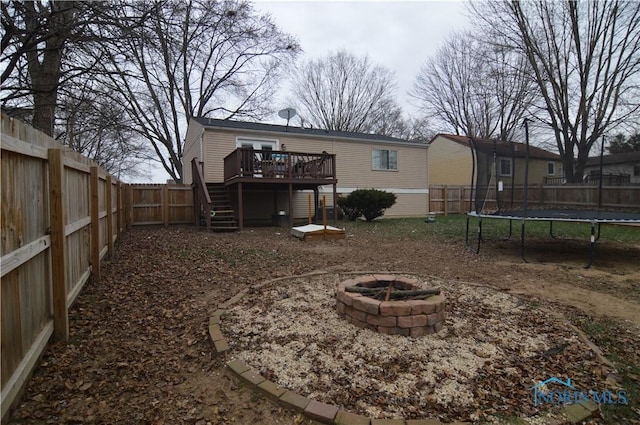 view of yard with a trampoline, a deck, and an outdoor fire pit