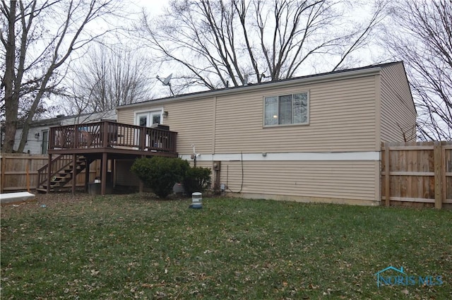 rear view of house featuring a lawn and a deck