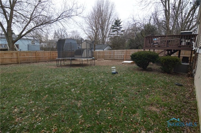 view of yard with a wooden deck and a trampoline