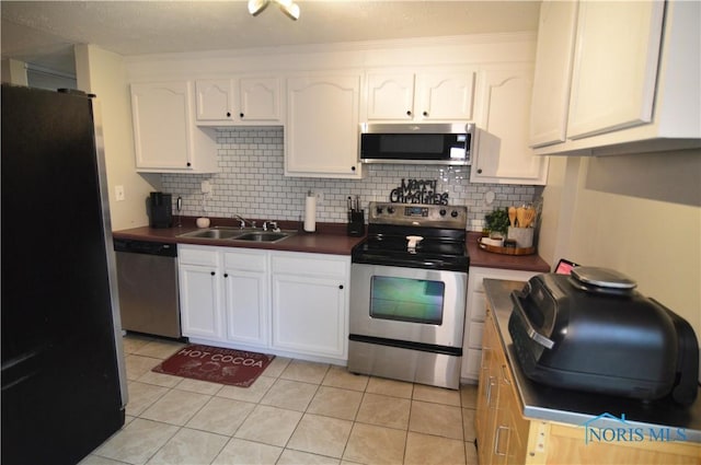 kitchen with white cabinetry, sink, light tile patterned floors, and appliances with stainless steel finishes