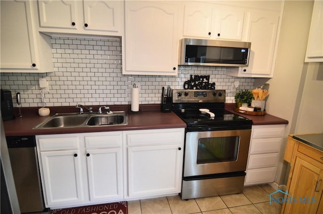 kitchen featuring sink, stainless steel appliances, light tile patterned floors, tasteful backsplash, and white cabinets