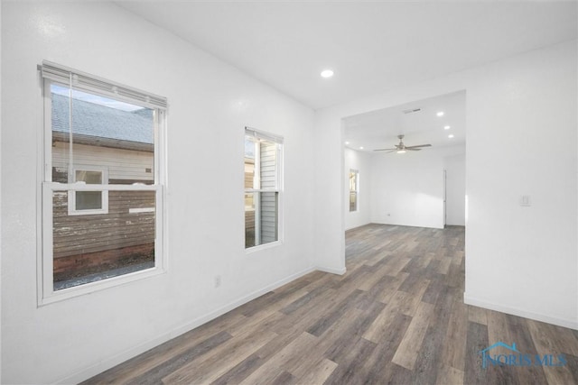 unfurnished room featuring a healthy amount of sunlight, ceiling fan, and dark wood-type flooring