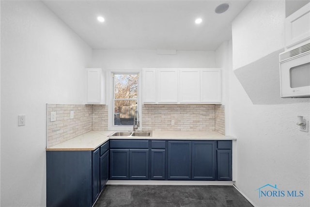 kitchen featuring blue cabinetry, sink, white cabinetry, and backsplash