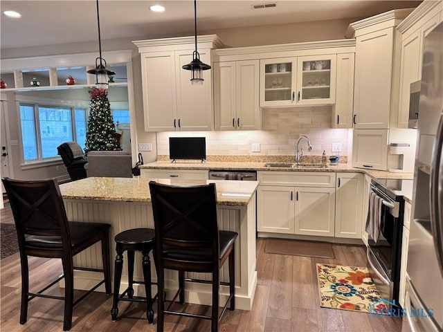 kitchen with a kitchen bar, sink, decorative light fixtures, and light hardwood / wood-style flooring