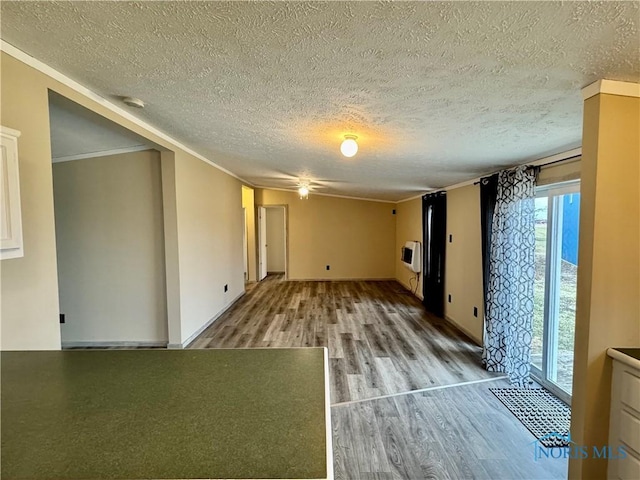 spare room with hardwood / wood-style flooring, crown molding, a textured ceiling, and heating unit