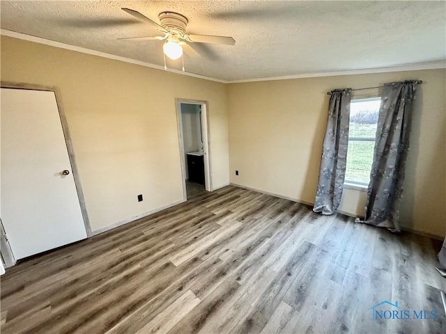 unfurnished bedroom featuring a textured ceiling, ensuite bathroom, ceiling fan, and ornamental molding