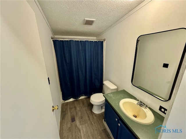 bathroom featuring a shower with curtain, vanity, a textured ceiling, hardwood / wood-style floors, and toilet