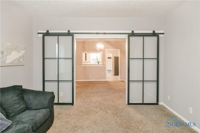 carpeted living room featuring a barn door and a textured ceiling