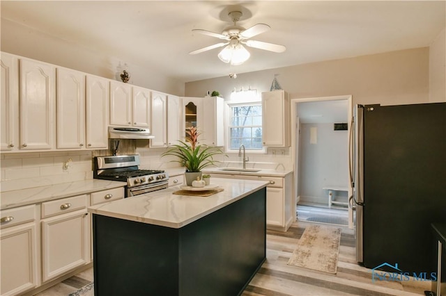 kitchen with a center island, sink, ceiling fan, light wood-type flooring, and appliances with stainless steel finishes