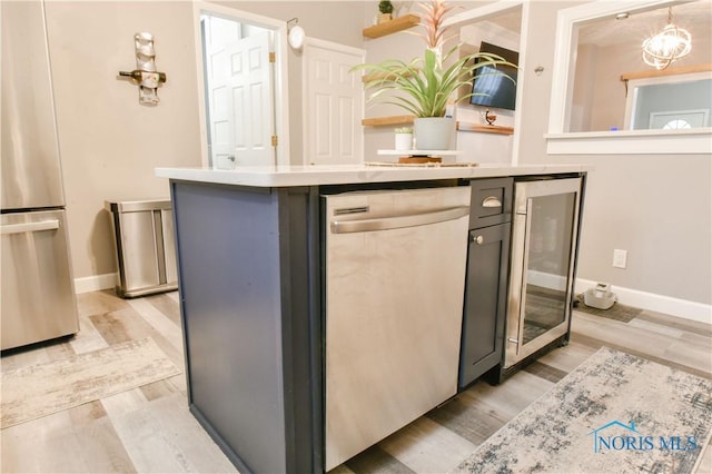 kitchen with pendant lighting, stainless steel appliances, wine cooler, and light hardwood / wood-style flooring