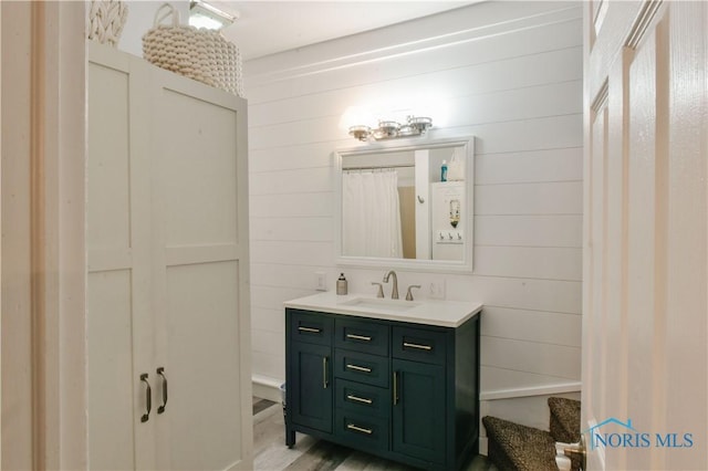 bathroom with vanity, wood-type flooring, and wooden walls